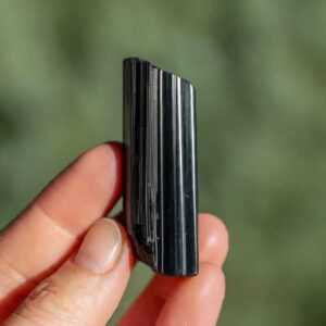A raw, elongated Black Tourmaline crystal