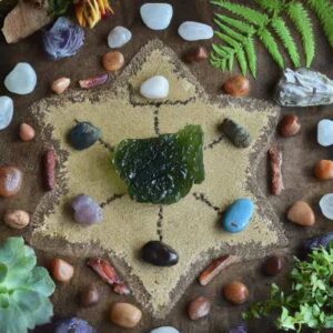 An image of a crystal grid with a large Moldavite specimen in the center, surrounded by grounding stones and other supportive crystals.