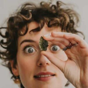 A close-up photo of a person holding a Moldavite crystal with a mix of curiosity, excitement, and perhaps a hint of awe reflected in their eyes.