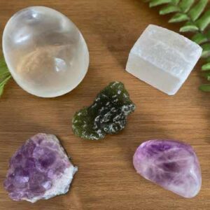 A photo of a crystal collection with a Moldavite specimen alongside gentler stones such as Clear Quartz, Amethyst, and Selenite, highlighting the option of alternatives.
